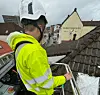 Mann i lift inspiserer stormskade på hustak