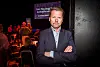 Mann i dress står foran en scene med fair play-presentasjon i bakgrunnen