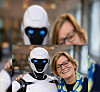 Portrettfoto av Kirsti Kierulf, stående ved siden av en humanoid robot