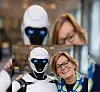 Portrettfoto av Kirsti Kierulf, stående ved siden av en humanoid robot