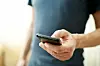 En mann står med en mobiltelefon i sin ene hånd. Han ser ut til å sjekke innholdet på skjermen.