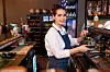 Kaféansatt lager cappuccino ved en espressomaskin i en bar eller kafé.