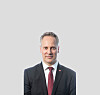 Portettfoto av ham, sett mot nøytral/grå bakgrunn