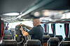 Mann som setter et batteri inn i en ryggbåren støvsuger, for å støvsuge i en buss.