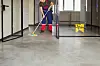 Mann som mopper gulvbelegg i et kontorlandskap med glassdører og -vinduer.