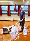 En mann sliper ned et linoleumsgulv med en spesialmaskin.