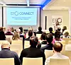 Konferansedeltakere ser en presentasjon på skjerm under seminaret EFCI Connect. En kvinne står ved talerstolen, mens publikum har ryggen til kamera.