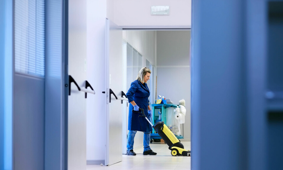 Avstandsbilde av kvinnelig renholder som jobber alene i en lang korridor