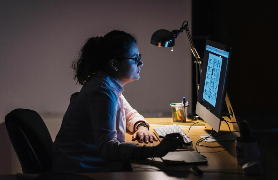 Kvinne som sitter foran dataskjerm i mørket, med et bygningskart på skjermen.