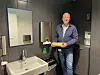Stig Helgesen viser fram en bunke håndtørkepapir, i et toalettrom
