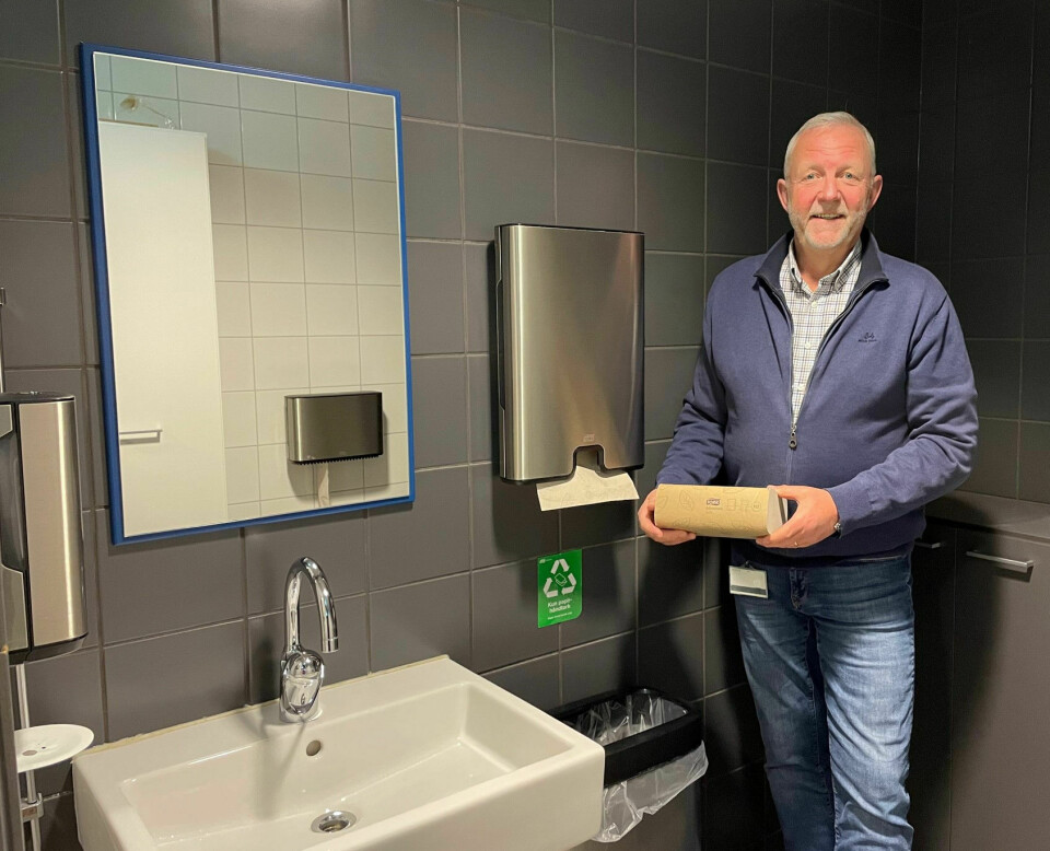 Stig Helgesen viser fram en bunke håndtørkepapir, i et toalettrom