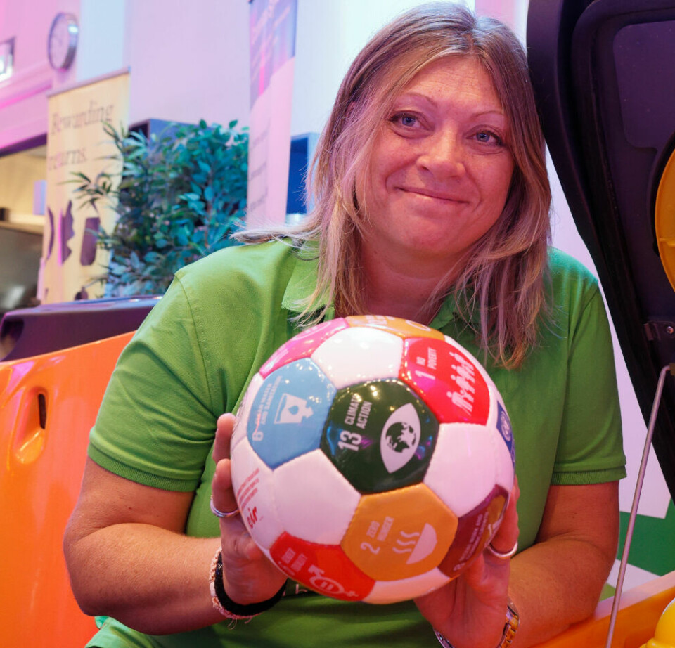 Hun viser en fotball med FNs bærekraftsmål